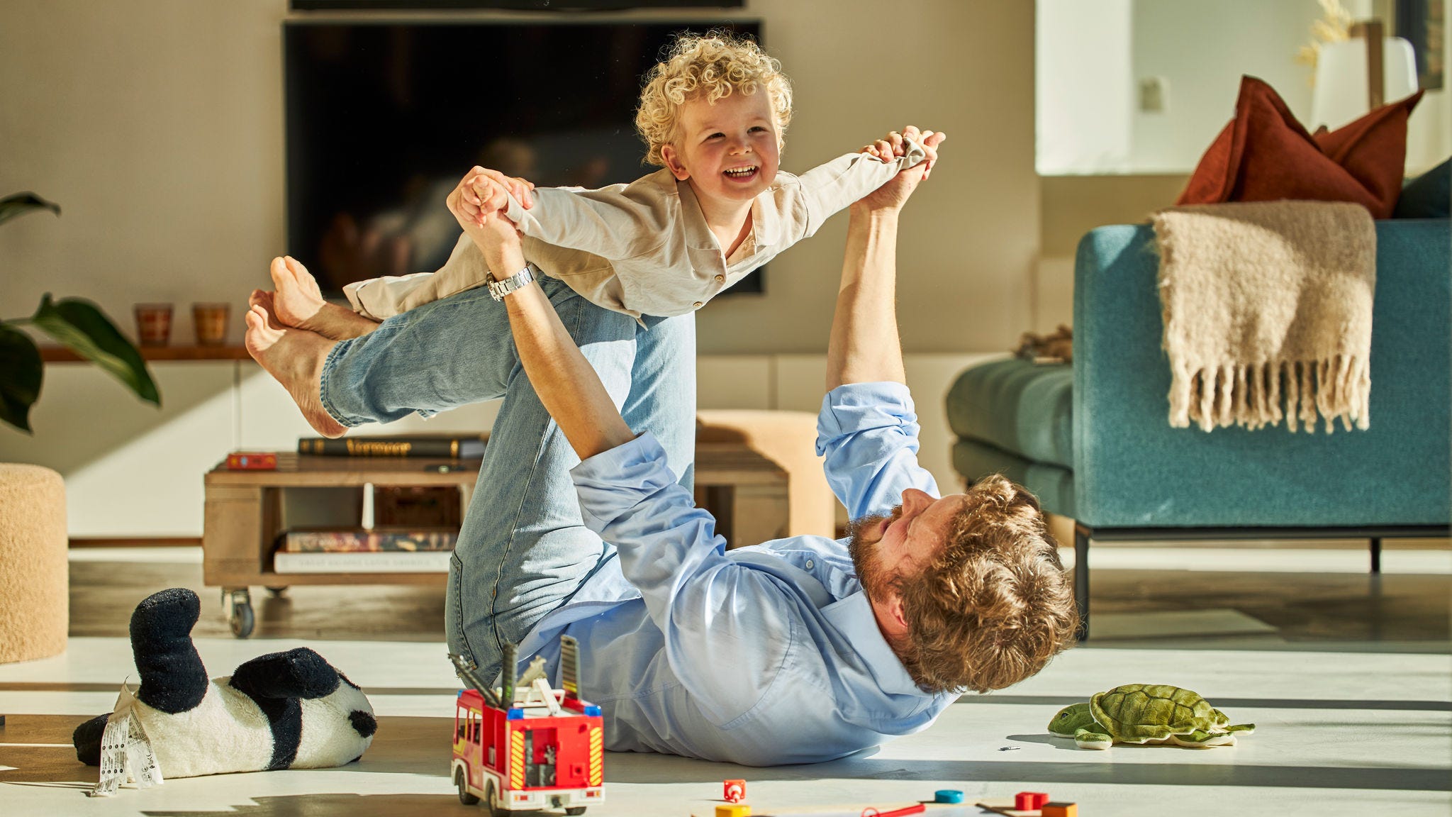 Otec a jeho dítě si spolu spokojeně hrají a užívají si tepla podlahového vytápění