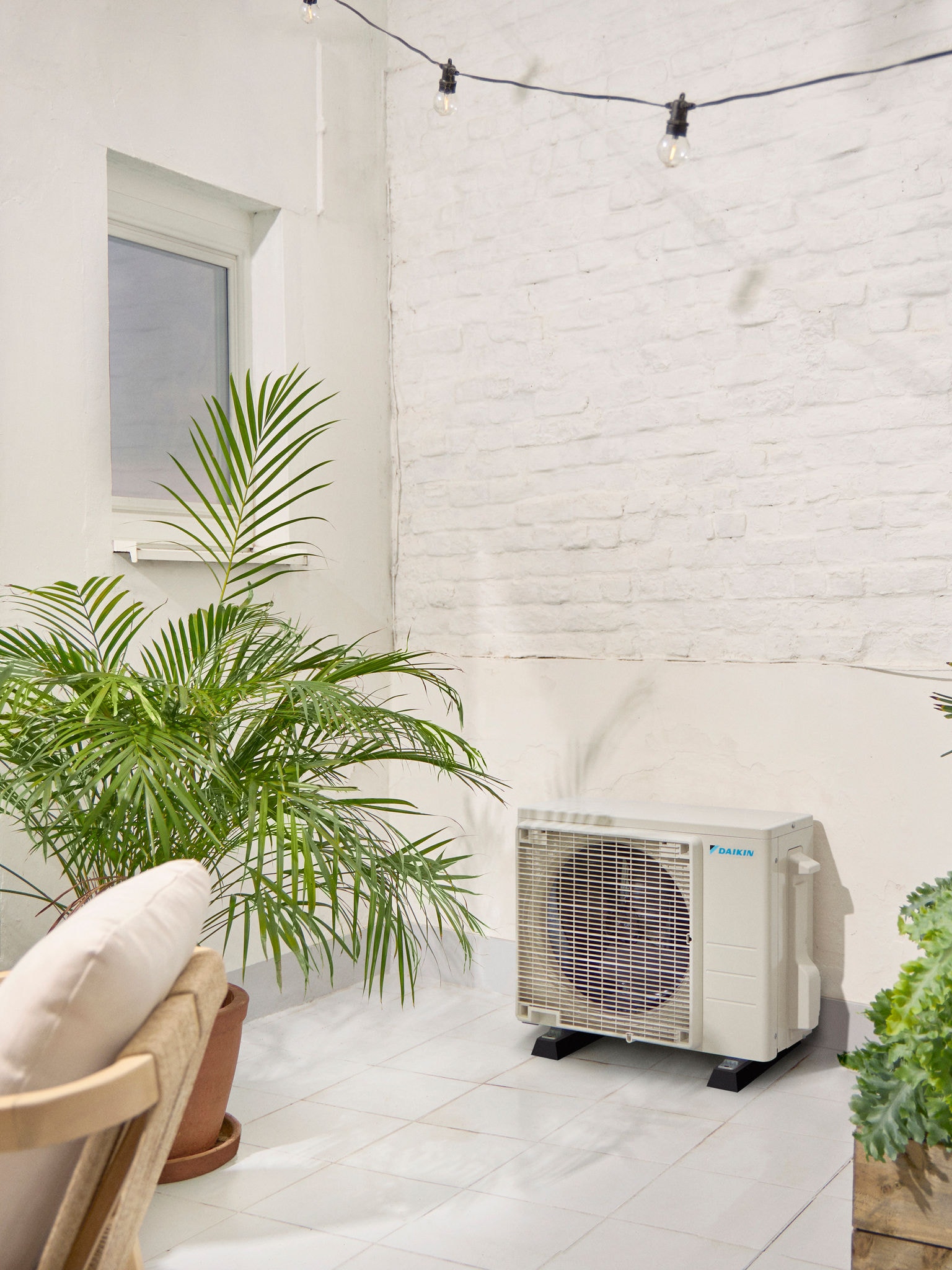 Venkovní jednotka Daikin na bílé terase s rostlinou