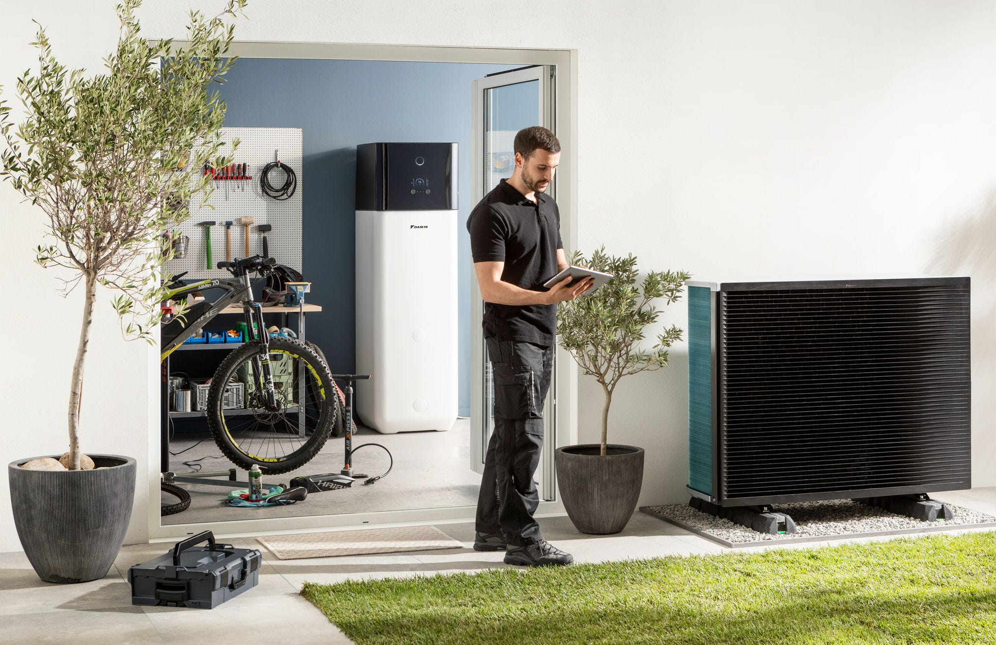 Montážní technik kontroluje venkovní jednotku tepelného čerpadla se zdrojem vzduchu a zásobník teplé vody