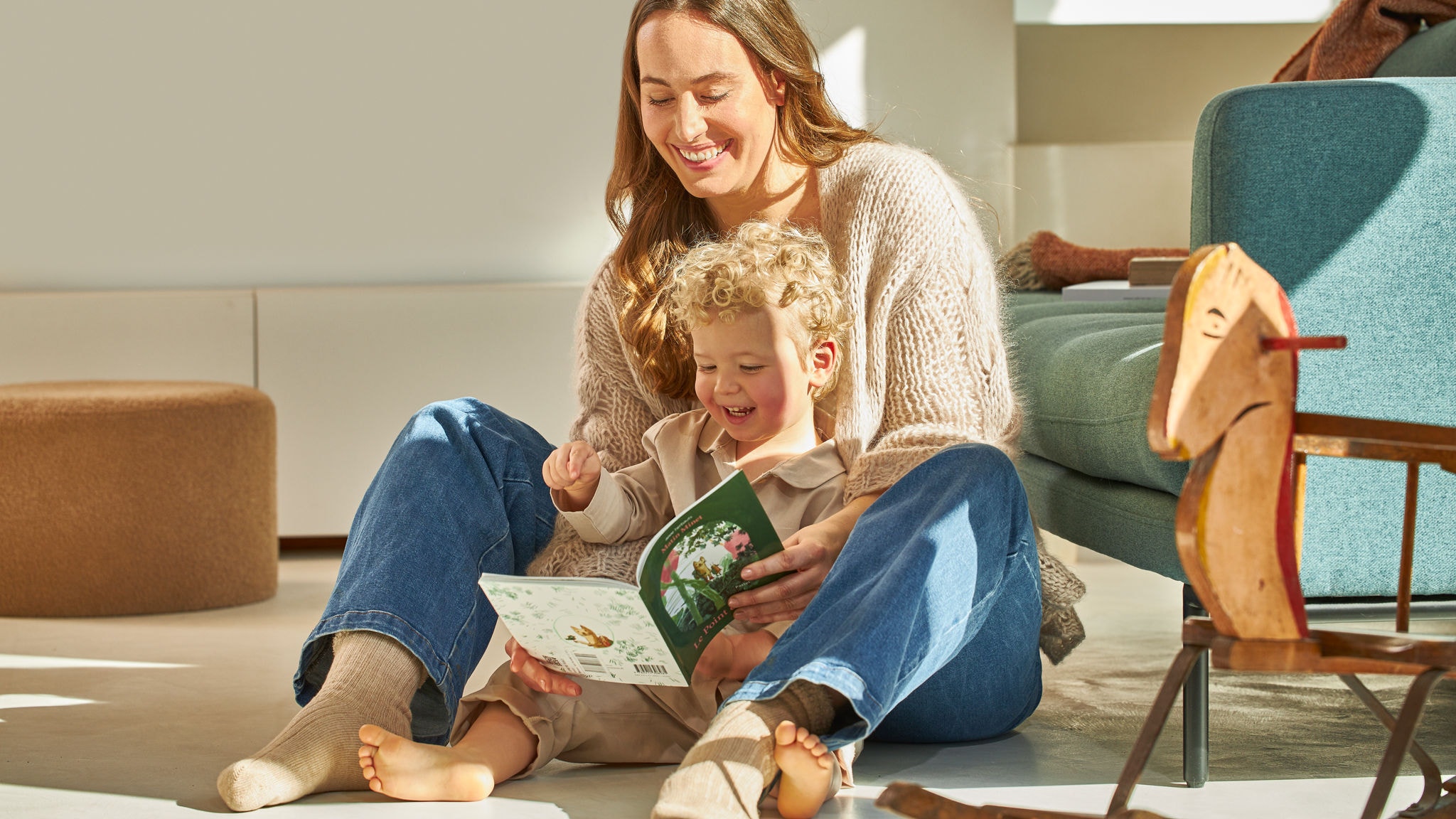 Matka a malý syn sedí, usmívají se a prohlížejí si knihu
