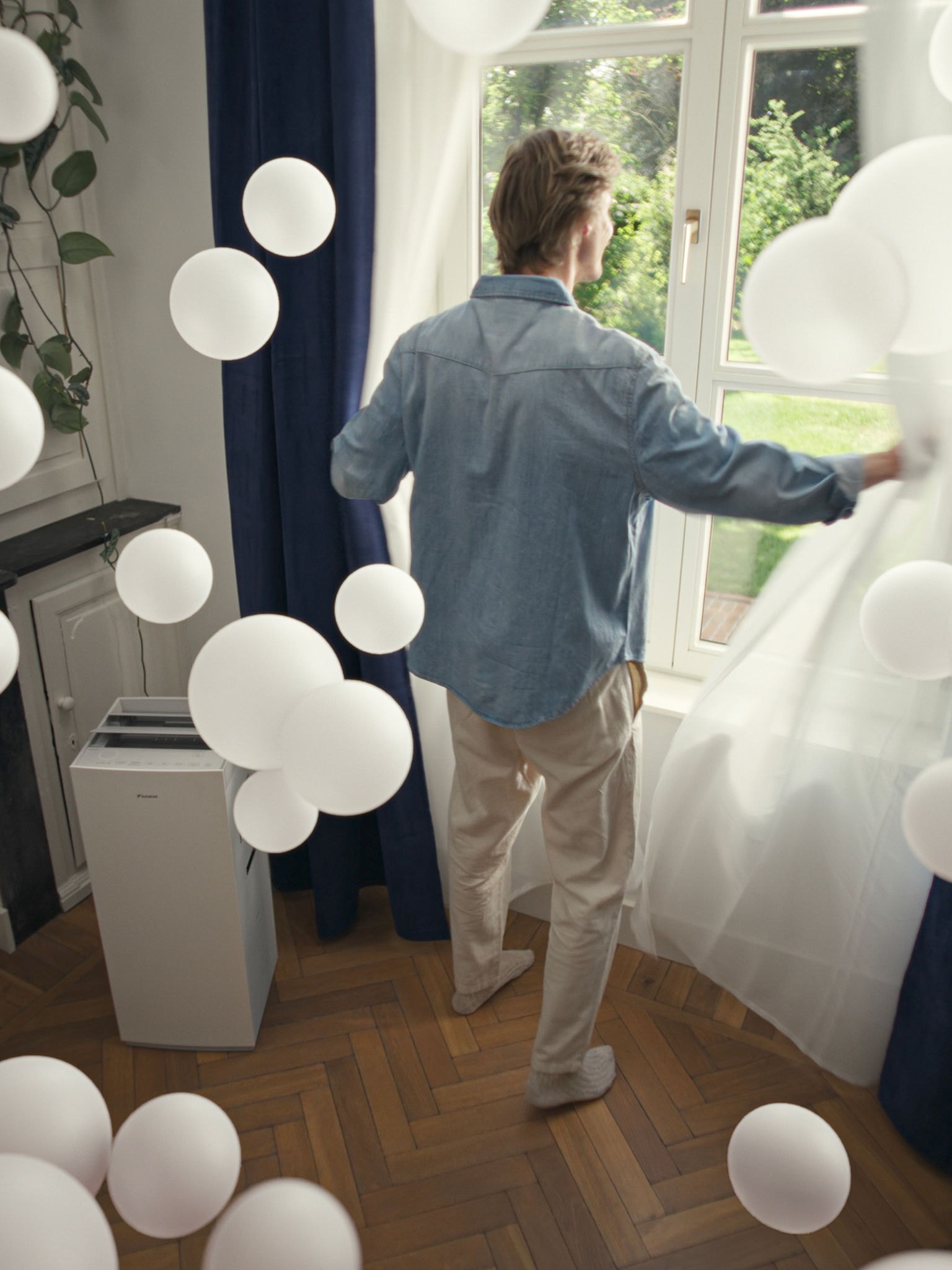 Starší muž cvičí na veslařském trenažéru v prostředí s čistým vzduchem a čističkou vzduchu