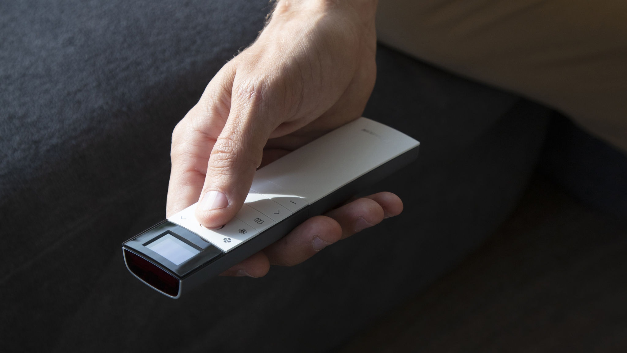 Muž ovládá klimatizaci v obývacím pokoji dálkovým ovladačem