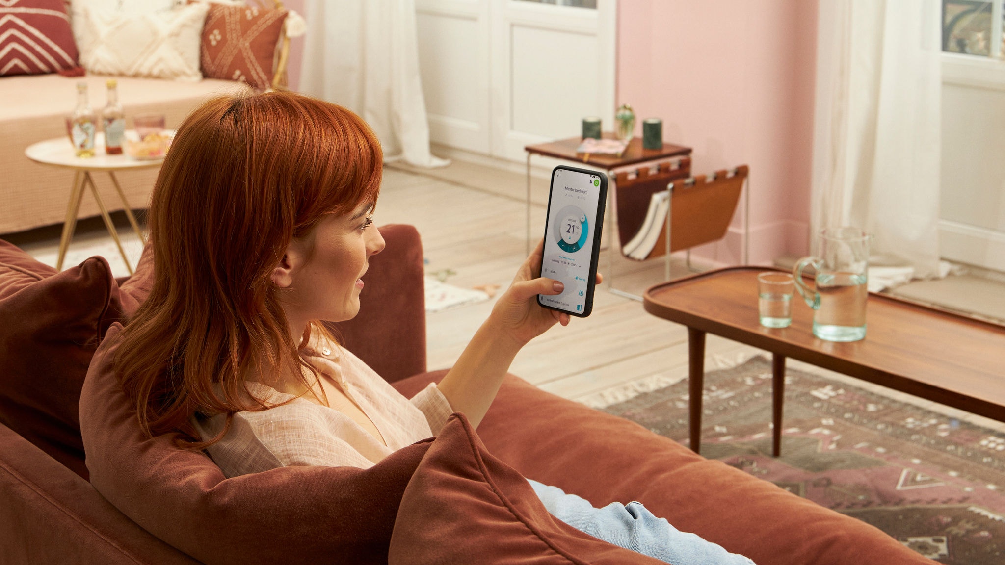 Žena sedící doma na pohovce a používající aplikaci Onecta na svém mobilním telefonu