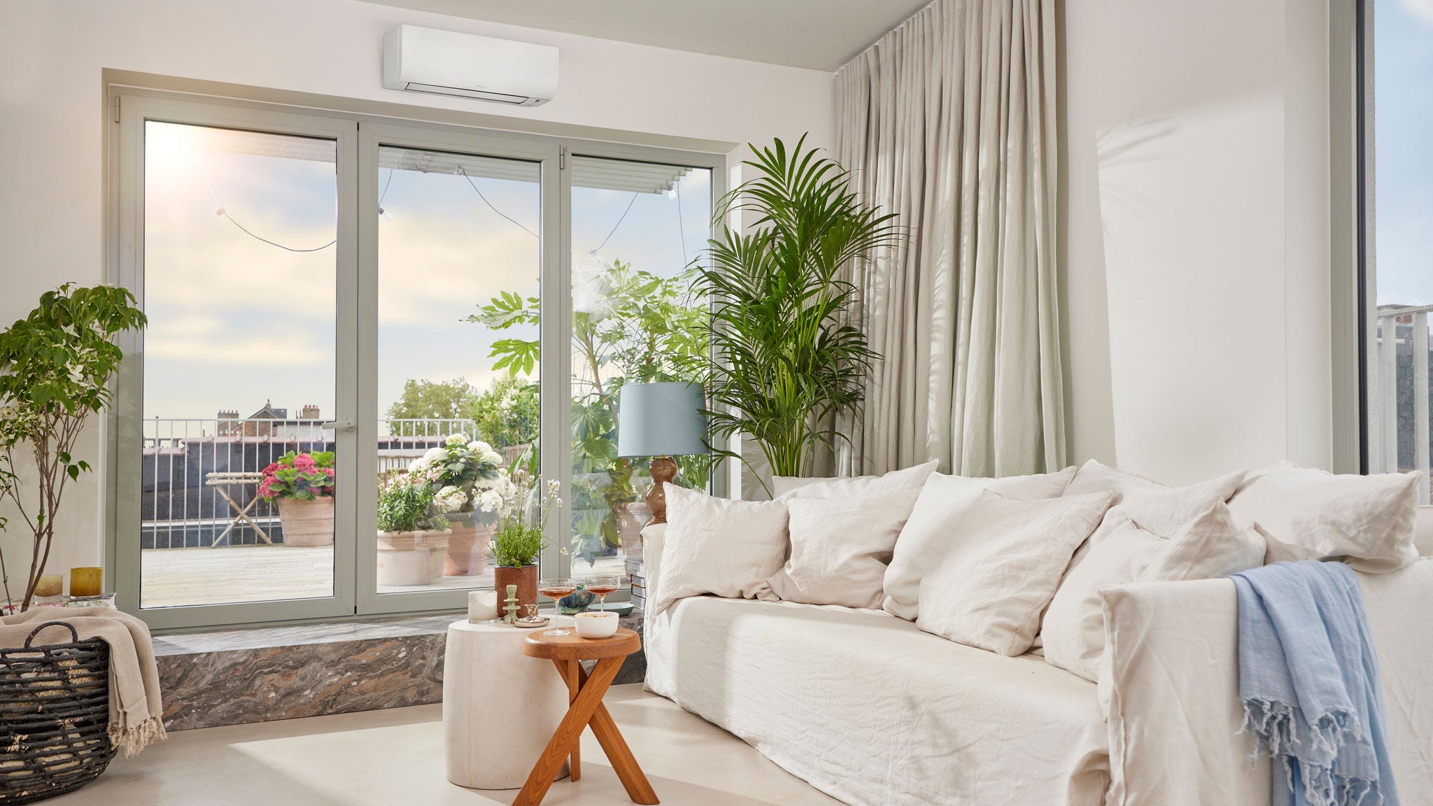 Světlá, vzdušná místnost s diskrétním bílým nástěnným tepelným čerpadlem vzduch-vzduch, které zajišťuje jak vytápění, tak chlazení