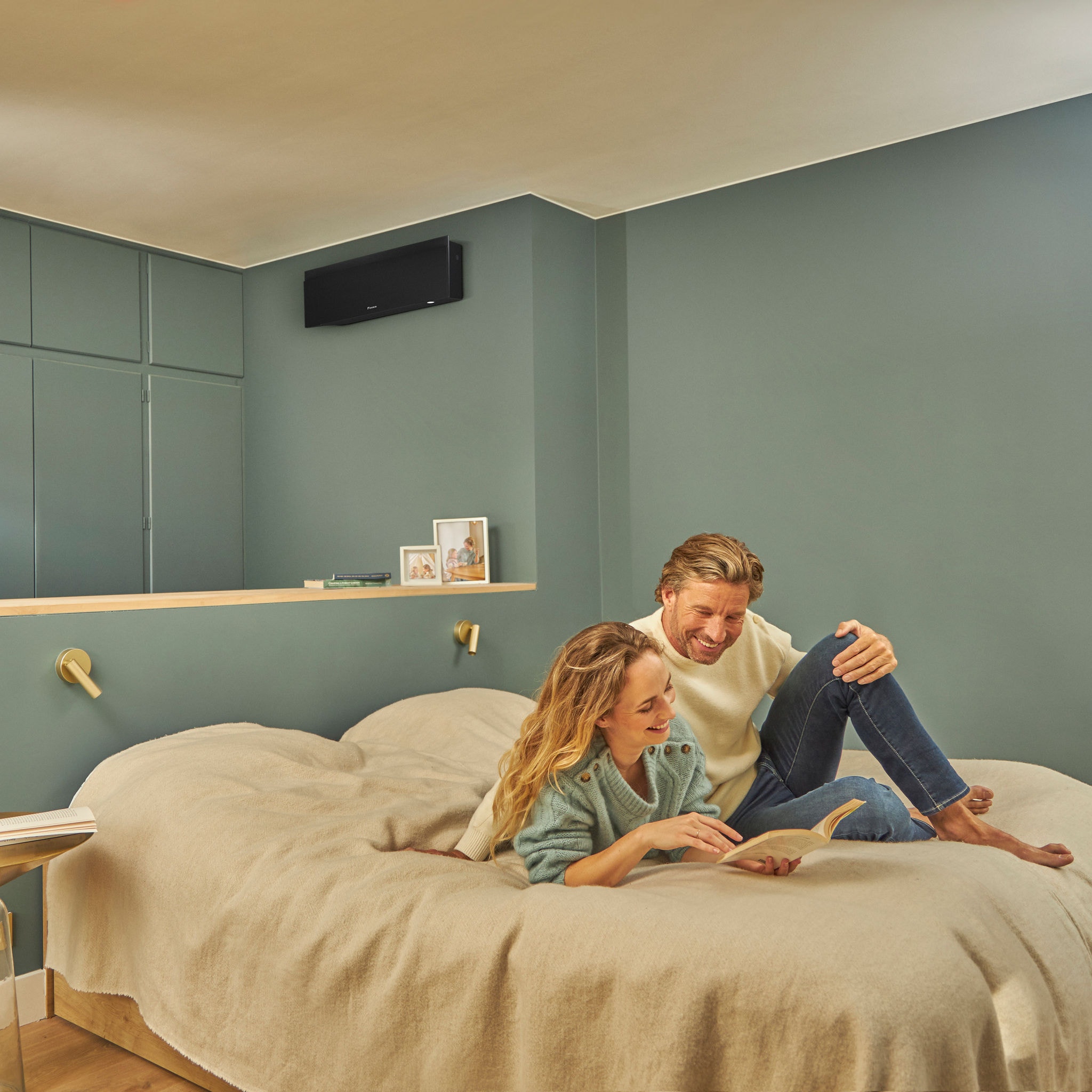 Smiling couple cuddling on their bed in perfect temperature thanks to their wall-mounted climate solution