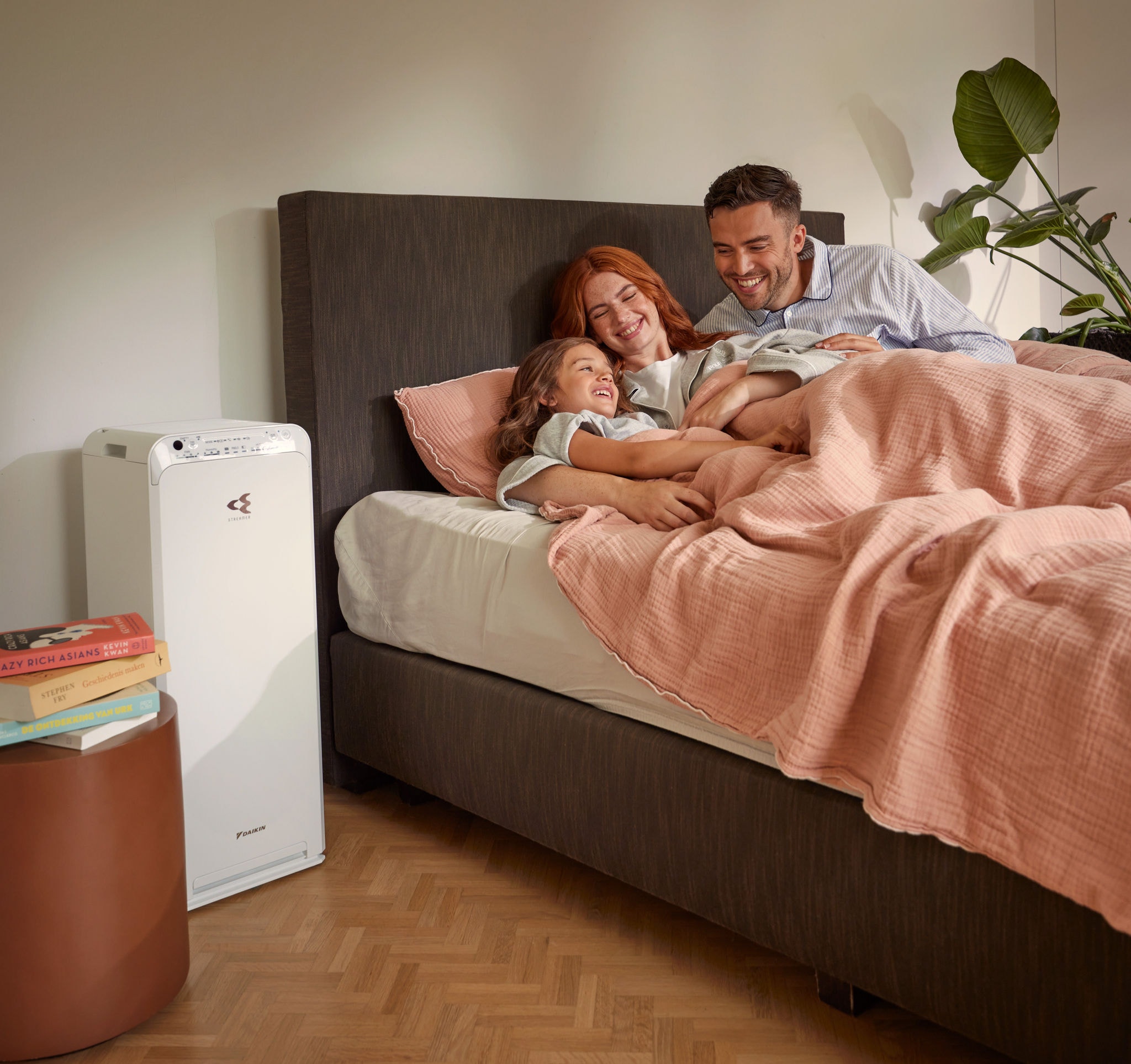 Pár s dítětem relaxuje v ložnici a užívá si čistý vzduch s čističkou vzduchu.