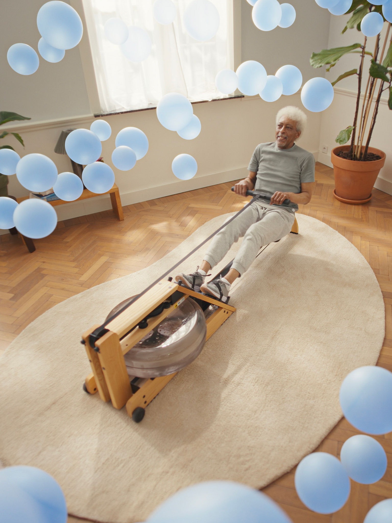 Starší muž cvičí na veslařském trenažéru v místnosti s dokonale klimatizovaným prostředím díky citlivé technologii tepelného čerpadla vzduch-vzduch