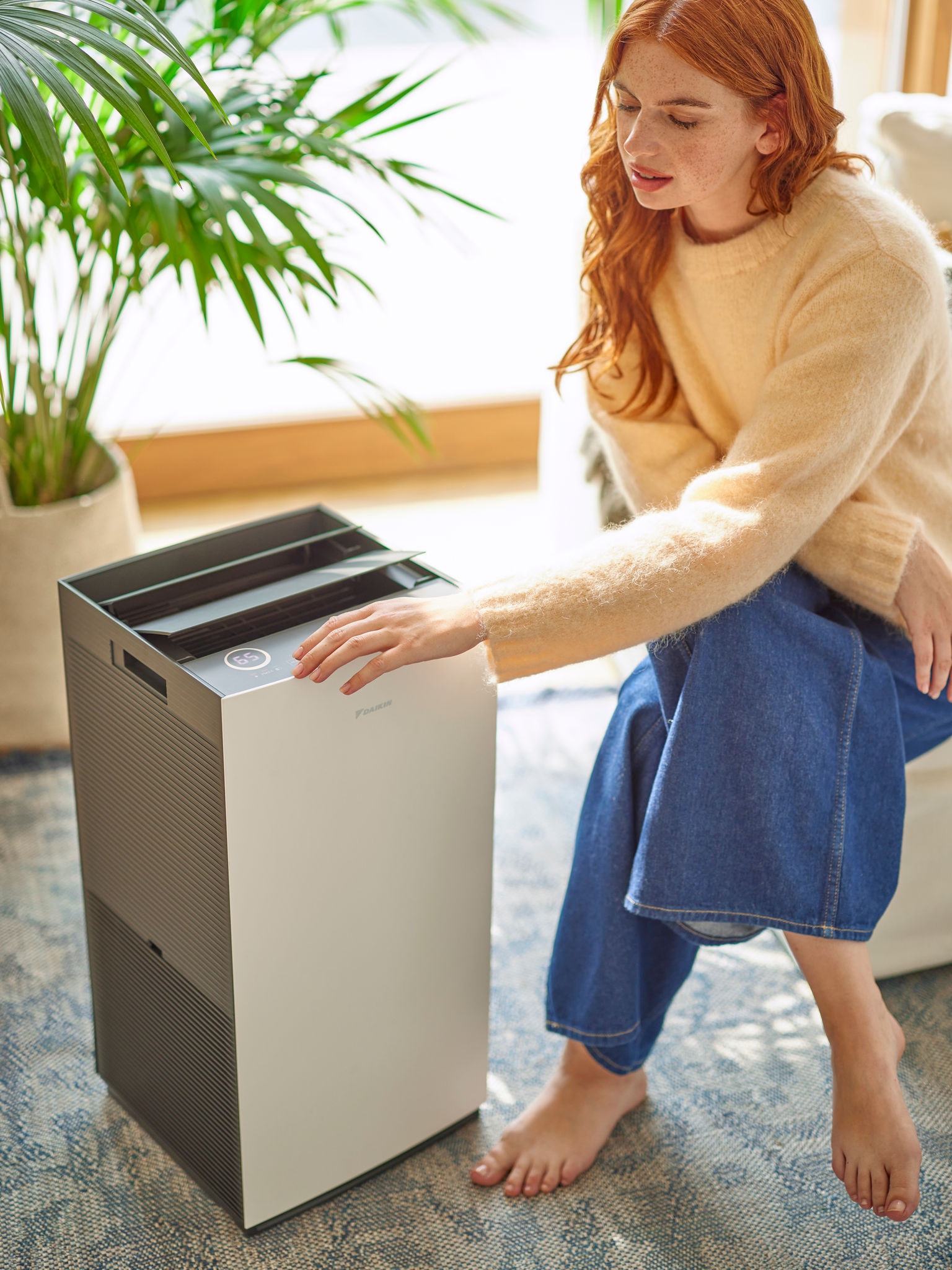 Žena v obývacím pokoji nastavuje ovládání čističky vzduchu Daikin