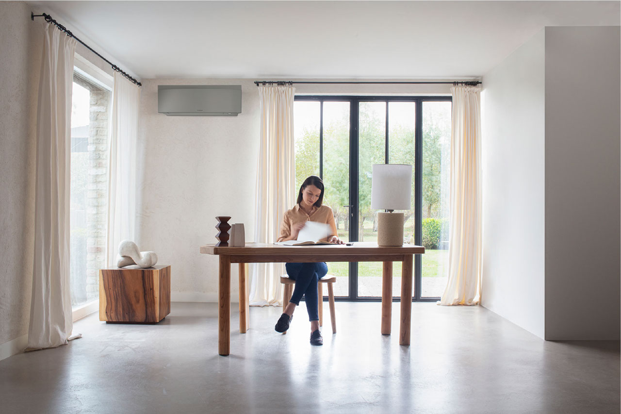 Person working on a desk with a FTXJ-AS unit in the background